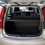 Offener, leerer Kofferraum eines silbernen Autos mit umgeklappten Rücksitzen, parkend an einem sonnigen Tag.