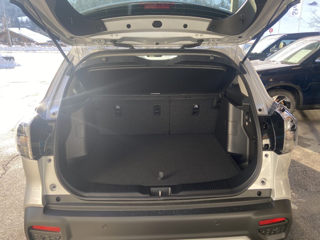 Offener Kofferraum eines weißen SUV, gezeigt in einem sonnigen Freiluftparkplatz.