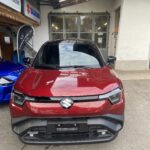 Roter Suzuki SUV vor Autowerkstatt mit Suzuki-Logo, fotografiert von vorne.