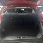 Offener Kofferraum eines roten Autos, fokussiert auf den Stauraum im Heckbereich.