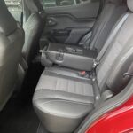 Rückbank und Innenraum eines modernen Autos mit roten Akzenten und heruntergeklappter Mittelarmlehne.