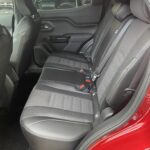 Rückbank eines modernen Autos mit schwarz-grauen Sitzen und roten Sicherheitsgurten in einem roten Fahrzeug.
