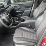 Innenraum eines neuen Autos mit modernen Sitzen und Lenkrad, Seitenansicht der Fahrerseite.