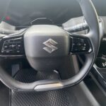 Lenkrad eines Suzuki mit Bedienelementen. Moderne Fahrzeugtechnik im Innenraum mit Multifunktionstasten.
