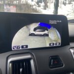Autodisplay zeigt 360-Grad-Kameraansicht beim Rückwärtsfahren, mit Umgebungsüberprüfung und Schneelandschaft im Hintergrund.