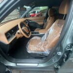 Moderner Autoinnenraum mit braunen Ledersitzen, geschützt mit Plastikfolie. Steuerkabine in Nahaufnahme.