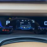 Digitales Armaturenbrett eines Autos mit Geschwindigkeitsanzeige, Parkmodus und Warnleuchten.
