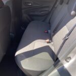 Rückbank eines Autos mit grauem Stoffbezug, geräumig und komfortabel für Passagiere, Autofenster im Hintergrund.