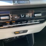 Klimaanlagenbedienfeld eines Autos mit Temperaturanzeige auf 18 Grad und eingeschaltetem Beifahrerairbag.
