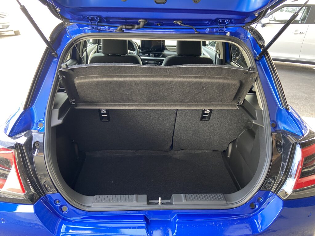Geöffneter Kofferraum eines blauen Autos, zeigt geräumigen Innenraum und umklappbare Rücksitze.