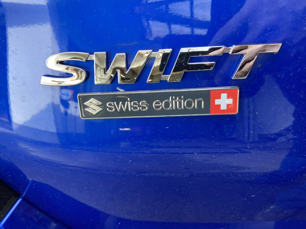 Detail eines blauen Autos mit „SWIFT“ und „Swiss Edition“ Emblemen.