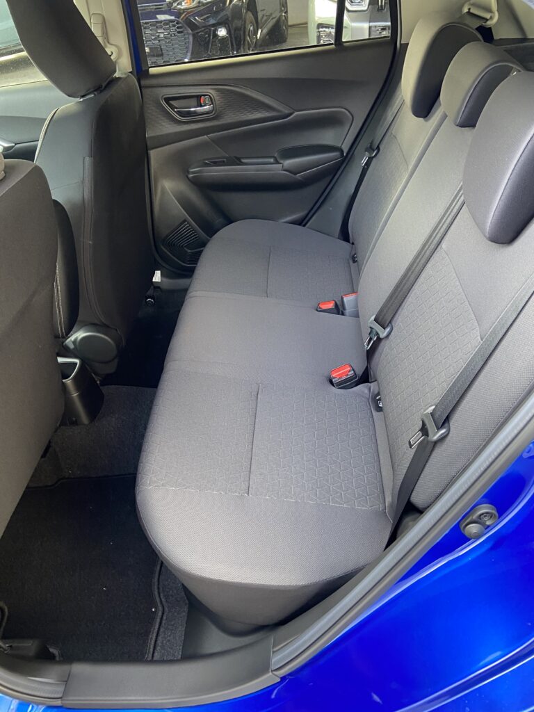 Rückbank eines blauen Autos mit grauen Polstern, zeigt geräumiges und modernes Interieur.