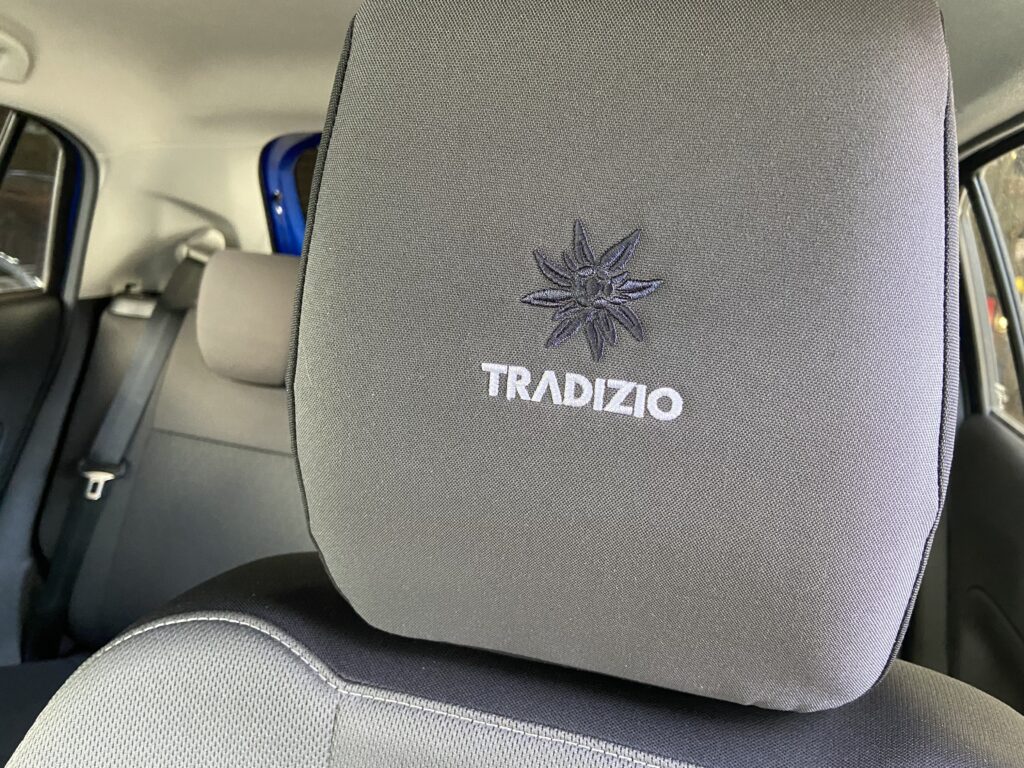 Autositz mit besticktem TRADIZIO-Logo und floralem Muster im Innenraum eines Fahrzeugs.