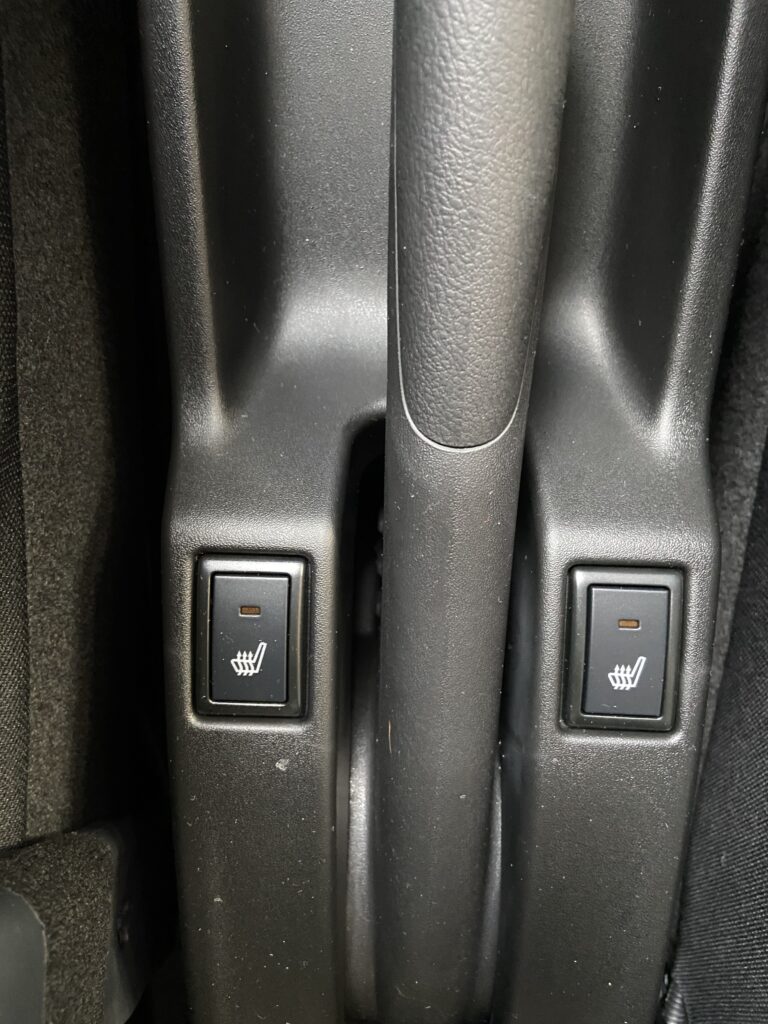 Zwei Schalter für Sitzheizung in einem Fahrzeug, Detailansicht der Mittelkonsole.