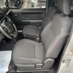 Innenansicht eines Autos mit grauen Stoffpolstersitzen und Blick auf geparkte Fahrzeuge draußen.