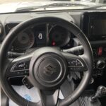 Lenkrad eines Suzuki-PKWs, Innenansicht mit Tachometer, Handschaltung und Multifunktionstasten.
