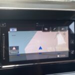 Navigationssystem im Auto zeigt Karte mit Standort und Straßennamen an, Uhrzeit 13:20 sichtbar.