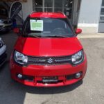 Roter Suzuki Ignis vor Autohaus, ideales Stadtauto bei Tageslicht geparkt.