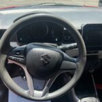 Innenansicht eines Suzuki-Autos mit Lenkrad und Armaturenbrett bei Sonnenschein.