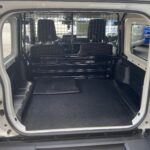 Leerer Laderaum eines weißen Transporters mit Gitterabtrennung zur Fahrerkabine, geeignet für Ladetransporte.