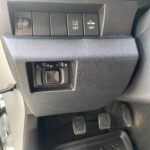 Autoinnenraum: Armaturenbrett mit verschiedenen Tasten und Pedalen im Fußraum.
