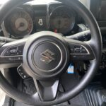 Lenkrad und Armaturenbrett eines Suzuki Autos, Nahaufnahme des Innenraums.