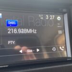 Auto-Digitalradio zeigt Sender DAB1 bei 216,928 MHz. Uhrzeit 3:27. Pioneer-Bildschirm mit Einstellungen und Suchoptionen.
