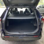 Geöffneter Kofferraum eines schwarzen Autos mit geräumigem Laderaum auf einem Parkplatz.