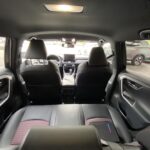 Innenansicht eines modernen Autos, Rückbank-Perspektive, mit hochwertigen Ledersitzen und digitalem Armaturenbrett im Vordergrund.