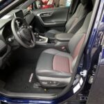 Moderner Autositz und Armaturenbrett mit Display in schwarzem Interieur, Blick auf die Fahrerseite.