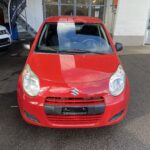Rotes Suzuki Auto, frontal auf einem Parkplatz bei einem Autohaus fotografiert.