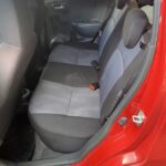 Rücksitzbank eines roten Autos mit schwarzen und grauen Polstern im sauberen Zustand.