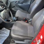 Innenraum eines Autos, Fokus auf Fahrersitz und Lenkrad eines roten Fahrzeugs in gutem Zustand.