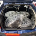 Auto-Kofferraum mit vier in Plastik verpackten Alufelgen, bereit für den Transport oder die Lagerung.