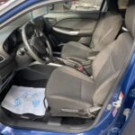 Innenraum eines blauen Autos mit schwarzen Sitzen und Armaturen, Ansicht von der Fahrerseite.