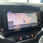 Navigationssystem im Auto mit digitaler Karte und Route auf dem Bildschirm, Uhrzeit 08:10, Warnsymbol aktiviert.