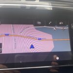 Navigationssystem zeigt Simmentalstrasse, Kleindorf, mit Autozoom Warnung auf dem Display eines Fahrzeugs.