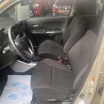 Innenraum eines Autos mit zwei Vordersitzen, Lenkrad und Fußmatte, schwarz-graue Sitze.