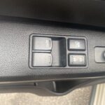 Autofensterbedienung mit Schalter für Kindersicherung, Spiegelverstellung und automatischem Fensterheber in Nahaufnahme.