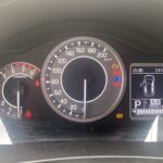Tachometer eines Autos, zeigt Geschwindigkeit, Drehzahl, Symbolleuchten und Kilometerstand an, betont offene Tür als Warnung.