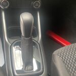 Automatikgetriebe in einem Auto mit USB-Anschluss und rotem Sicherheitswerkzeug auf dem Boden.