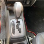 Automatikgetriebe in einem Auto mit verschiedenen Fahrstufen und rotem Rand am Fußraumteppich.