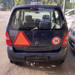 Blaues Auto mit rotem Dreieck und 30er Geschwindigkeitsschild auf dem Parkplatz vor grüner Waldlandschaft.