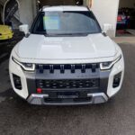 Weißer SUVs in einer Garage von vorne, modernes Design, Verkaufsschild an der Frontscheibe.