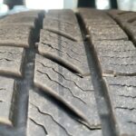 Nahaufnahme eines abgenutzten Autoreifenprofils, das die abgeflachte Struktur und Rillen zeigt.