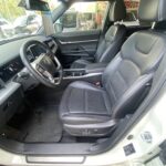 Moderner Autoinnenraum mit Ledersitzen und Armaturenbrett, Ansicht von der Fahrertür.