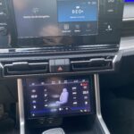 Fahrzeug-Infotainment-System zeigt Navigation und Klimatisierungseinstellungen auf zwei Bildschirmen.