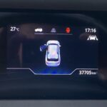 Fahrzeugdisplay zeigt geöffnete Tür, 27°C, Kilometerstand 37705, Sicherheitsgurtwarnung und Uhrzeit 17:16.