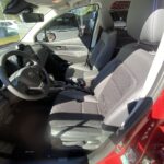 Interieur eines roten Suzuki Autos mit schwarzen Sitzen und moderner Ausstattung, Seitenfenster im Sonnenlicht.