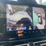 Auto-Rückfahrkamera-Display mit Umgebungssicht und Sicherheitshinweis auf Touchscreen im Fahrzeug.